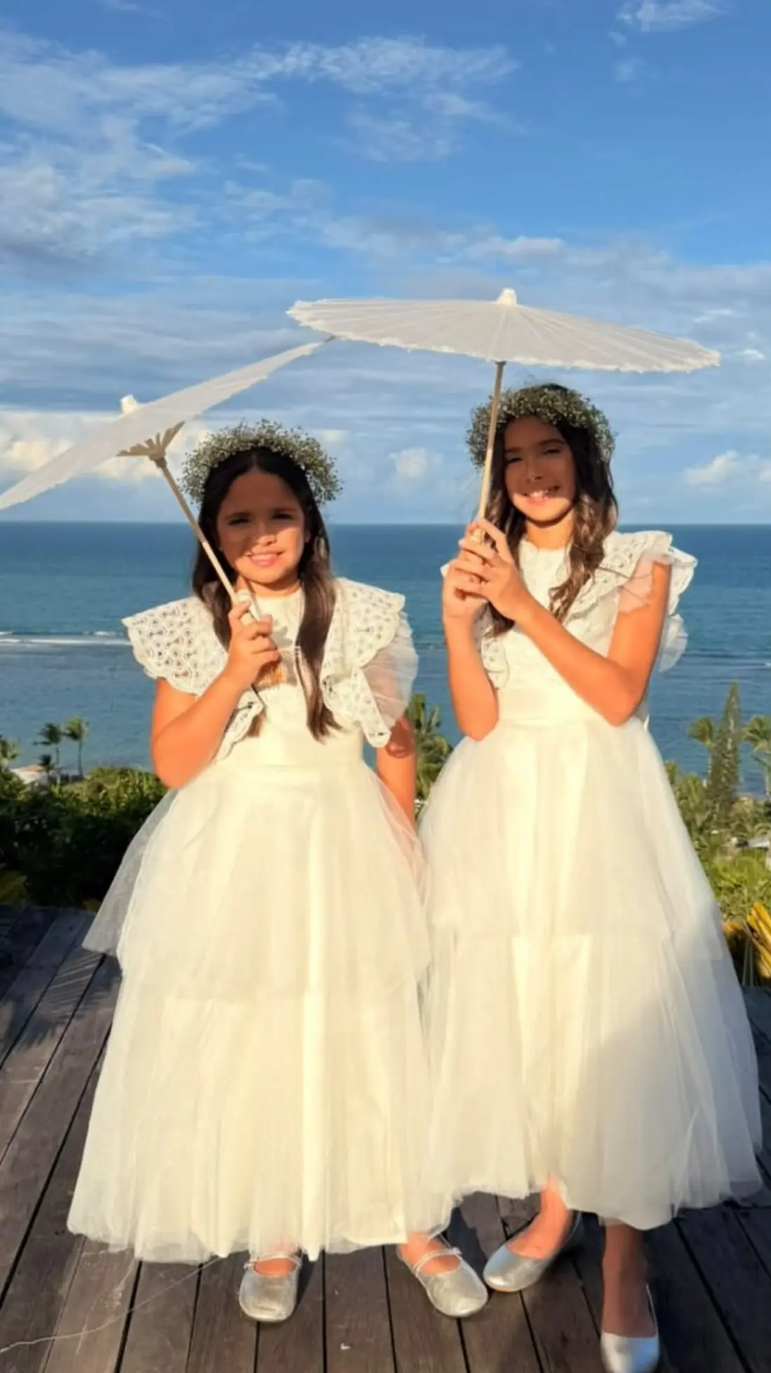 Damas de casamento com vestidos de renda e sombrinhas à beira-mar